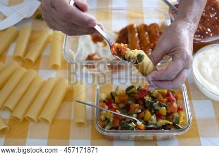 Two Human Hands Preparing Cannelloni With Vegetables And Meat Sauce. Cylindrical Shaped Pasta. Itali