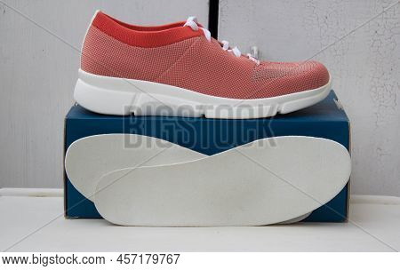 Sport Orange Shoe With White Lacing And Orthopedic Insoles Near The Blue Box. Treatment And Preventi