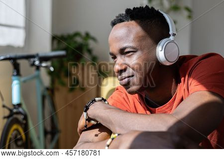 African Young Man Listening To Music While Relaxing On Sofa At Home - Thoughtful Millennial Guy Cont