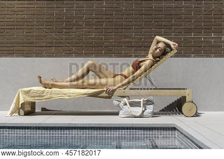 Full Body Young Fit Woman Relaxed Sun Bathing On A Wooden Sun Lounger Whearing A Bikini Swimwear
