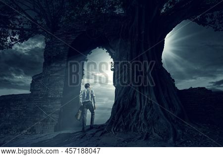 Businessman Looking Out Of Abstract Opening In Wall With Bright Daylight In Concrete Interior. Conce
