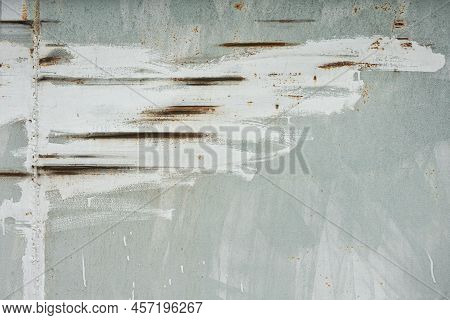 Scratches On A Gray Iron Wall Are Carelessly Smeared With White Paint. There Is A Weld And Rust Appe
