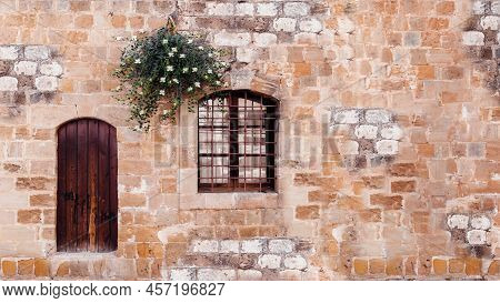 Old Door With Window And Flowering Caper Bush On Stone Wall, Horizontal Background.