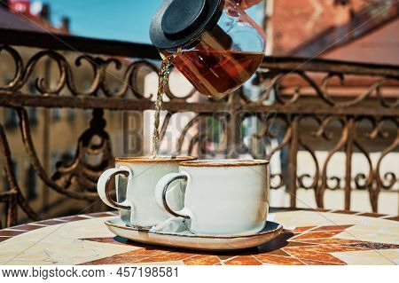 Tea In Glass Teapot Is Poured Into Cups, Tea Time, Old Cafe In The Center Of The Ancient City. Atmos