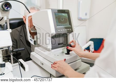 Doctor Examines Elderly Mans Eye On Screen Of Autorefractometer.