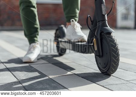 Woman In White Sneakers Is Standing On Electric Scooter