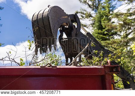 Close Up View Of The Hydraulic Arm And Scoop Bucket Of A Heavy Excavator Machine, Filling A Large Re