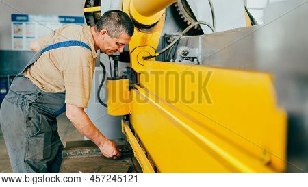 Worker Cuts Metal Sheets On Mechanical Guillotine Machine In Production Hall. Industrial Equipment F