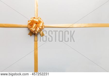 Top View Of Gold Ribbon Rolled And Yellowbow Isolated On Colored Background. Flat Lay With Copy Spac