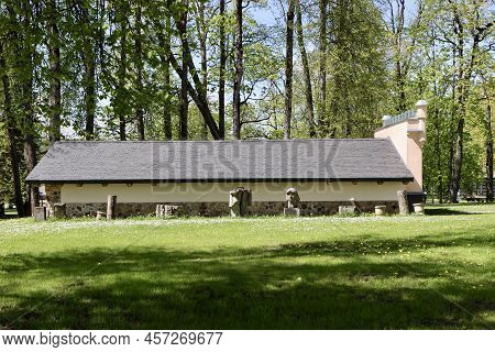 Outbuilding By New Palace In Aluksne Town, Latvia, And Some Sculptures In Front Of It. Aluksne, Latv