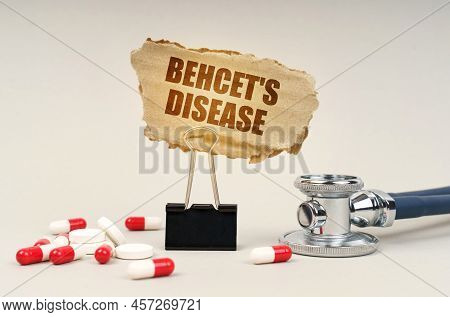 Near The Stethoscope Are Pills And A Clip With A Cardboard Sign - Behcets Disease