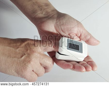 Woman Using Modern Fingertip Pulse Oximeter On Light Background, Closeup. Woman Hand With Fingertip 