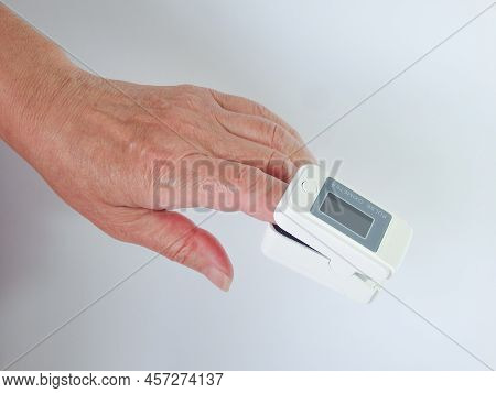 Woman Using Modern Fingertip Pulse Oximeter On Light Background, Closeup. Woman Hand With Fingertip 