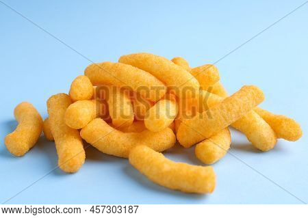 Heap Of Tasty Cheesy Corn Puffs On Light Blue Background, Closeup View
