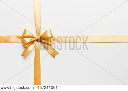 Top View Of Gold Ribbon Rolled And Yellowbow Isolated On Colored Background. Flat Lay With Copy Spac