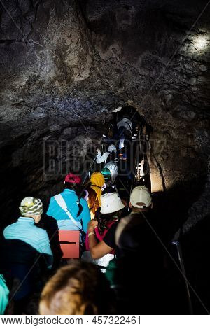 Tourists In The Cave Walk In A Crowd Along A Narrow Passage, An Expedition Of Speleologists Studies 