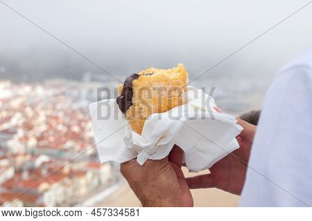 Portuguese Donut In Man Hands With View On City Nazare