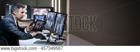 Businessman Talking On Walkie Talkie While Looking At Cctv Camera Footage On Multiple Computer Scree