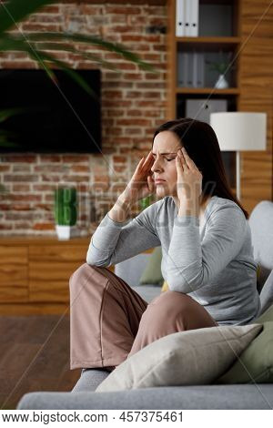 Upset Young Woman Suffering From Headache. Exhausted Woman With Closed Eyes Massaging The Temples Ha