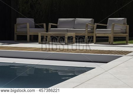 Lounge Area With Wooden Seating Sofa Near To The Swimming Pool Adge In Summer Time