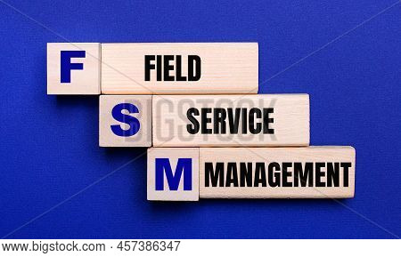 On A Bright Blue Background, Light Wooden Blocks And Cubes With The Text Fsm Field Service Managemen
