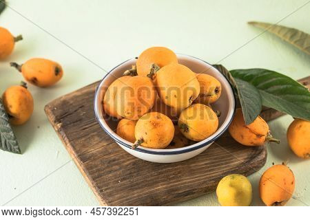 Ripe Medlar Fruit , Eriobotrya Japonica, And Green Medlar Leaves On Wooden Table. Top View