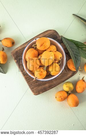 Ripe Medlar Fruit , Eriobotrya Japonica, And Green Medlar Leaves On Wooden Table. Top View