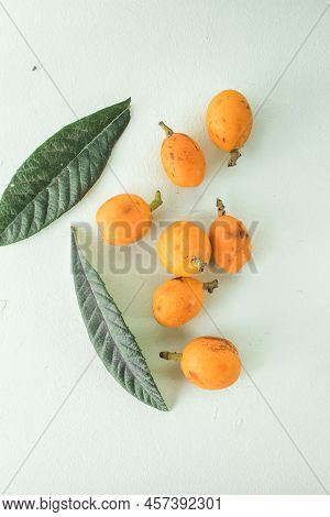Ripe Medlar Fruit , Eriobotrya Japonica, And Green Medlar Leaves On Wooden Table. Top View
