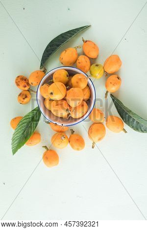 Ripe Medlar Fruit , Eriobotrya Japonica, And Green Medlar Leaves On Wooden Table. Top View