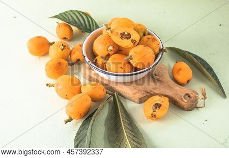 Ripe Medlar Fruit , Eriobotrya Japonica, And Green Medlar Leaves On Wooden Table. Top View
