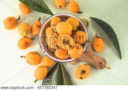 Ripe Medlar Fruit , Eriobotrya Japonica, And Green Medlar Leaves On Wooden Table. Top View