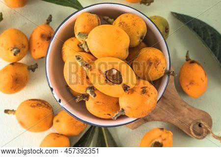 Ripe Medlar Fruit , Eriobotrya Japonica, And Green Medlar Leaves On Wooden Table. Top View