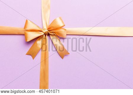 Top View Of Gold Ribbon Rolled And Yellowbow Isolated On Colored Background. Flat Lay With Copy Spac