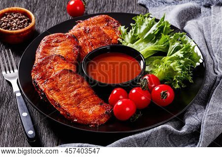 Grilled Slices Of Pork Loin Marinated In Paprika Based Sauce On Black Plate With Fresh Tomatoes And 