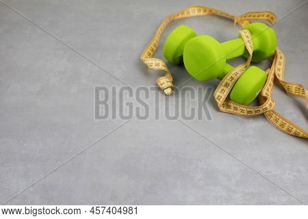 Dumbbells, Measuring Tape On A Gray Textured Background. Fitness, Sports Nutrition