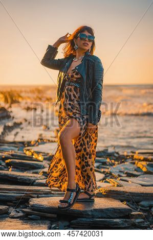 Summer Street Style On A Beach Next To Rocks Of A Young Brunette Caucasian Woman In A Leopard Dress 