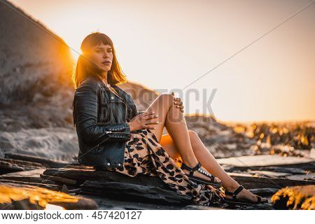 Summer Street Style On A Beach Next To Rocks Of A Young Brunette Caucasian Woman In A Leopard Dress 
