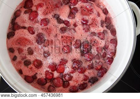Stage Of Making Homemade Strawberry Jam. Ripe Berries Boil With Sugar In Saucepan On Hob. Summer Tim