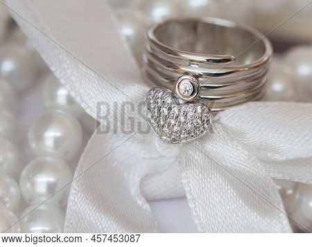 Close Up Of Dimond Ring  Heart Shape On The Table And Decorated With Pearl And Ribbin