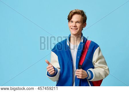 A Handsome Friendly Attractive Red-haired Young Man Student Stands With A Red Backpack And A Fashion