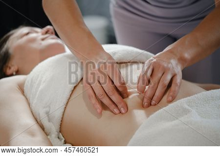 Top View Of Hands Massaging Female Abdomen. Therapist Applying Pressure On Belly. Woman Receiving Ma