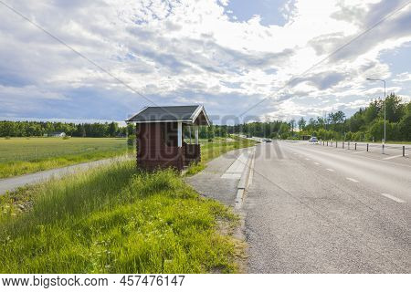 View Of Red Wooden Standard Bus Stop Outside City On Highway Against Backdrop Of Beautiful Natural L