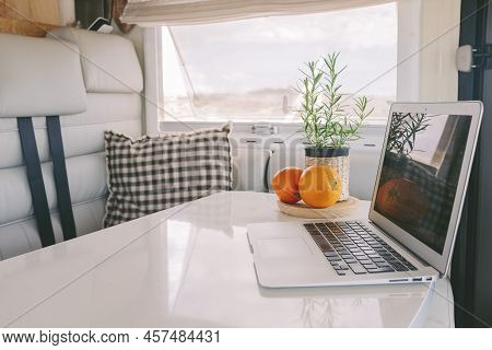 Interior View Of Modern Camper Van Vehicle With Emptu Elegant White Table And Laptop On It. Concept 