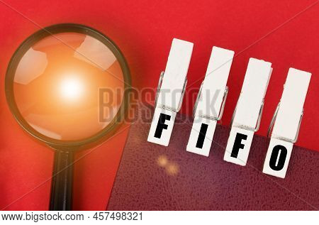 Business Concept. On The Red Surface There Is A Magnifying Glass, A Notepad And Clothespins With The