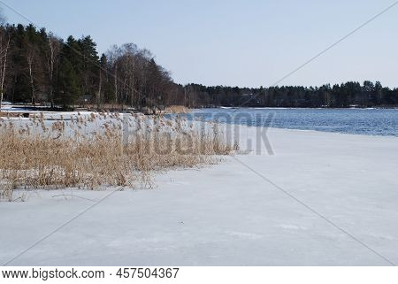 Snow-covered River Bank And Ice At The Edge Of The Coast. Spring Sunny Day, River Bank. Blue Sky And