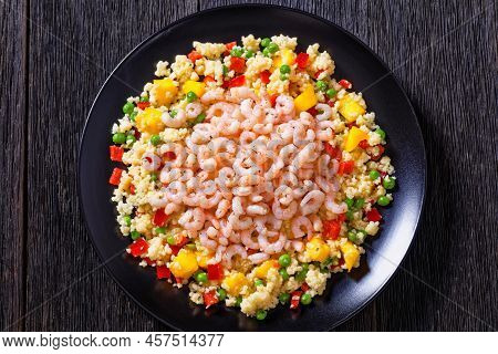 Cooked Small Pink Shrimps Topped Over Millet Pilaff With Vegetables, Mango Chunks And Spices On Blac