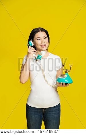 Charming Funny Asian Woman Using Vintage, Retro Telephone In Hands Wearing White T-shirt Isolated On