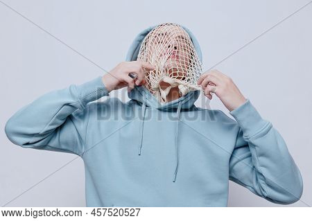 Tortured, Suffering From Problems, A Man With A Mesh On His Face Stands In A Light Blue Hoodie On A 
