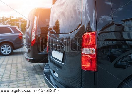 Close-up Detail Tail Light View Of Many Modern Luxury Black Vans Parked In Row At Car Sale Rental Le