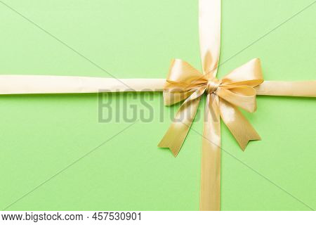 Top View Of Gold Ribbon Rolled And Yellowbow Isolated On Colored Background. Flat Lay With Copy Spac